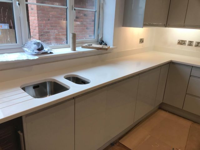 Quartz kitchen worktops and custom sink cutout with drainage grooves